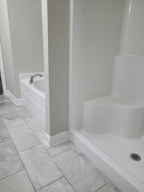 The same shower pan and seat bright white after cleaning, with the tub beyond